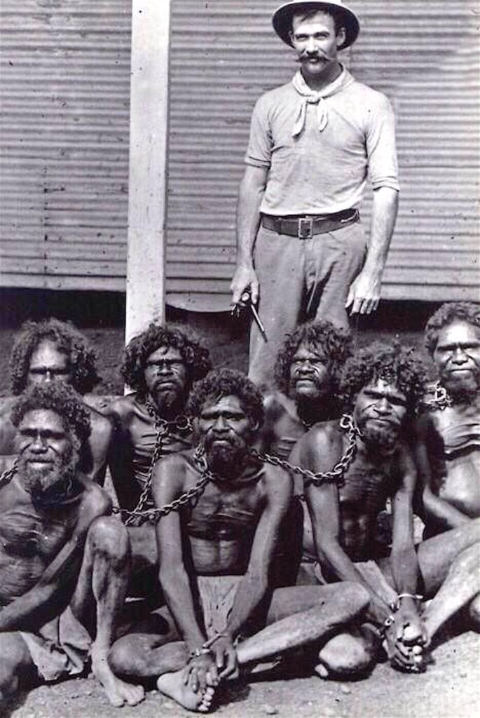 Aboriginal men are seen chained alongside a British convict during the 1900s. Credit: supplied.