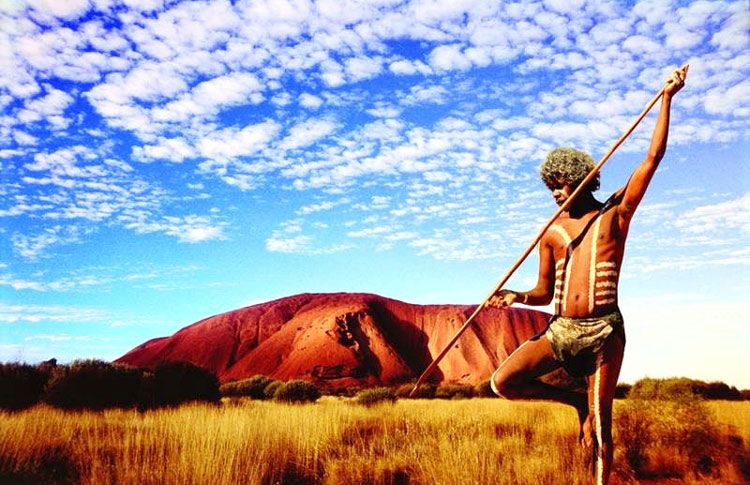 An Aboriginal man at Uluru, also known as Ayers Rock. The sandstone formation is a symbol of cultural identity, spirituality, and connection to the land for Aboriginal Australians, particularly the Anangu people. It is a place where traditions, stories, and ceremonies are kept alive and shared, making it one of the most culturally significant sites in Australia. Credit: Firstlighttravel.