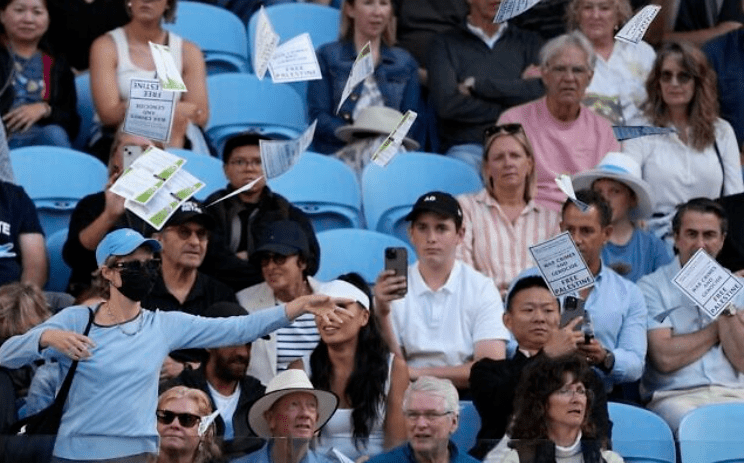 A woman throws "free Palestine" leaflets onto Margaret Court Arena during the fourth round match between Alexander Zverev of Germany and Cameron Norrie of Britain at the Australian Open tennis championships at Melbourne Park, Melbourne, Australia, Monday, Jan. 22, 2024. (AP Photo/Alessandra Tarantino)