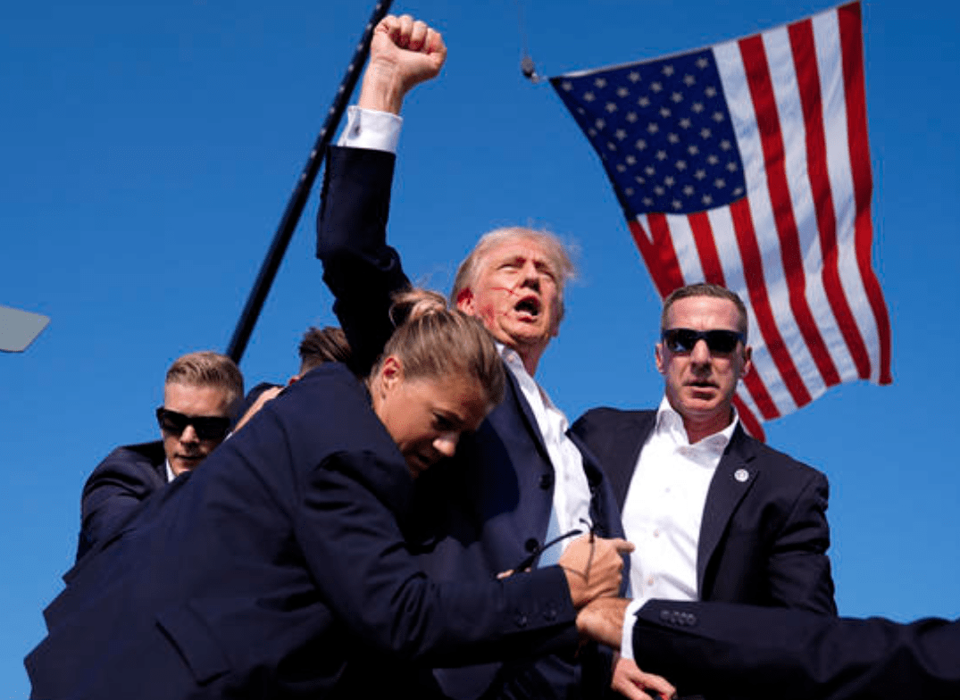 Former President Donald Trump is surrounded by U.S. Secret Service agents after apparent shots were fired at his campaign rally, July 13, 2024, in Butler, Pa.Credit: AP